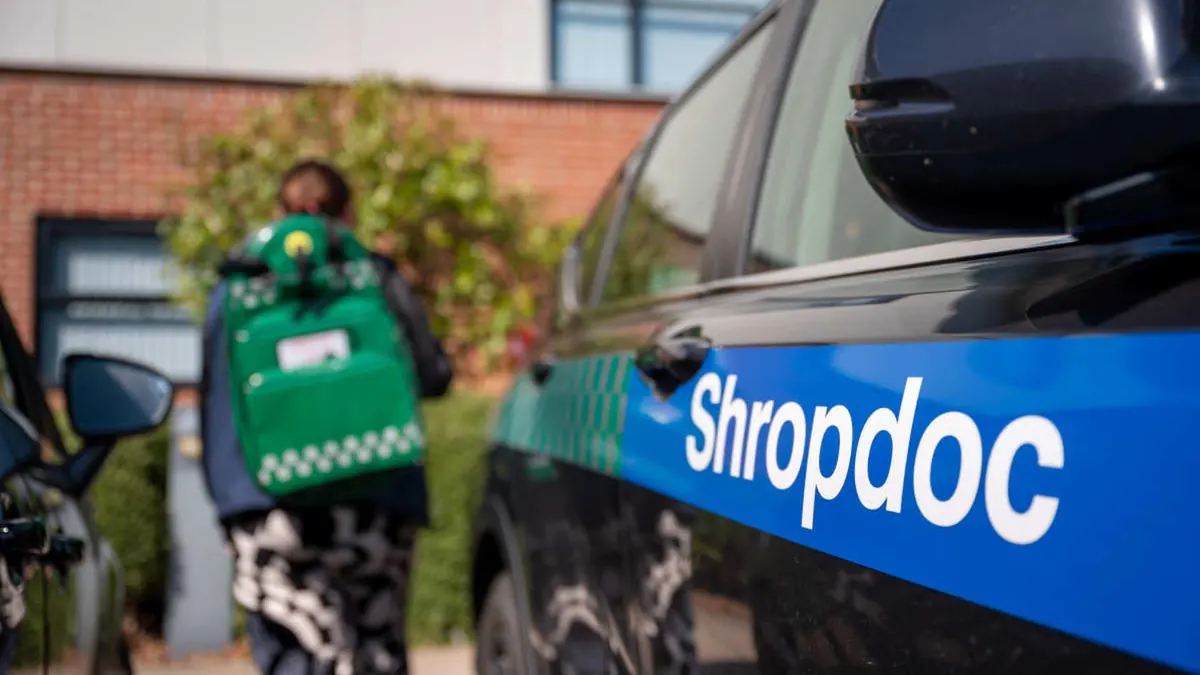 A Shropdoc clinician carrying an emergency response bag to a branded response car